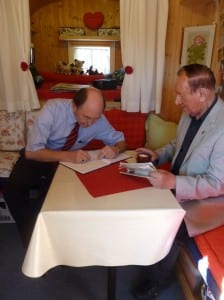 Der Bürgermeister und seine Begleiter tragen sich ins "Goldene Buch der Globetrotter" ein